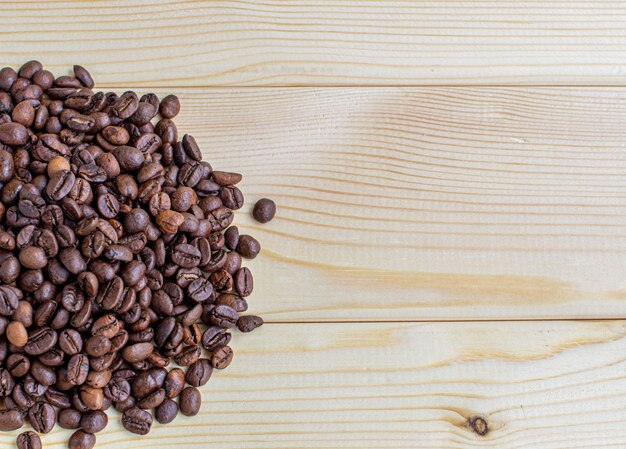 木製の背景にたくさんのコーヒー豆。挿入する場所があります。