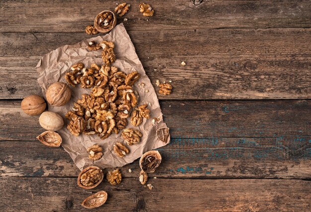 Lots of peeled and whole nuts on a wooden surface