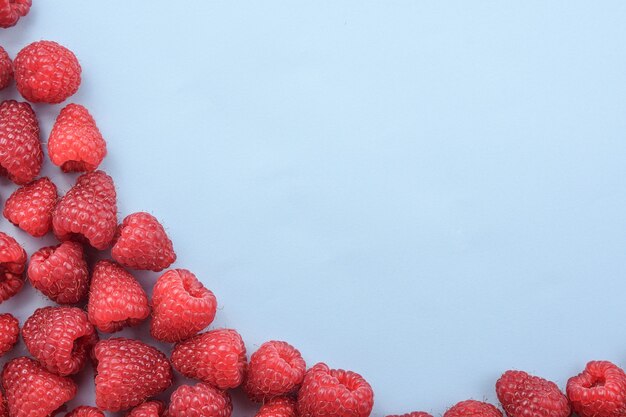 Lots of raspberries on a blue background.