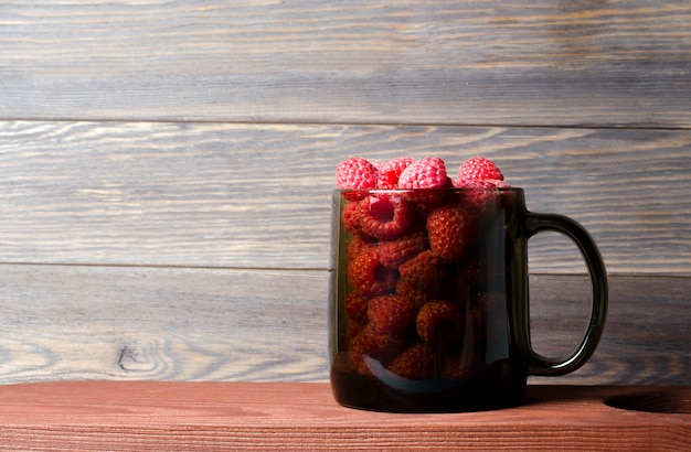 Lots of red ripe raspberries in a glass Cup. 