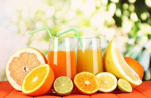 Lots ripe citrus with juices on wooden table on natural background