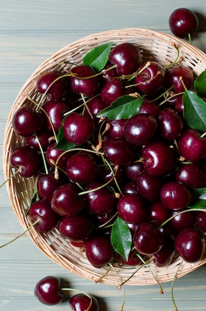 Lots of ripe red cherries in a wicker basket. 