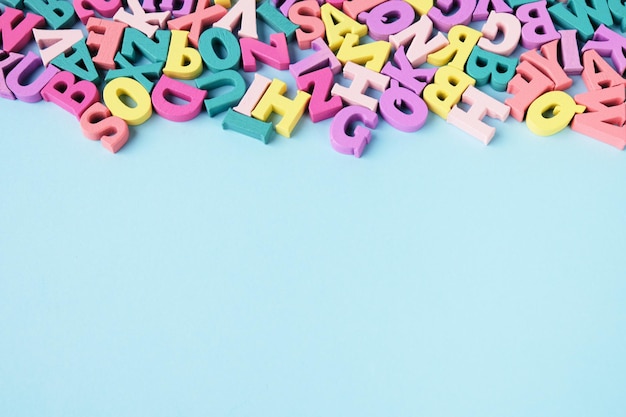 Lots of scattered multicolored letters on blue background Learning to read alphabet