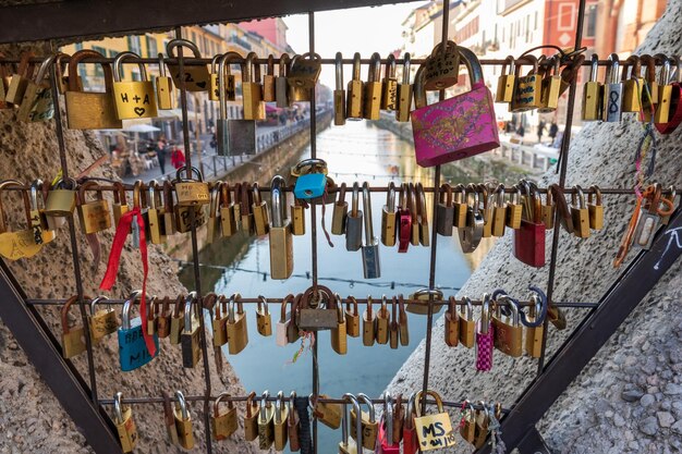 Foto un sacco di chiavi piccole e ad incastro sulla ringhiera del ponte e una vista dell'acqua del canale attraverso il