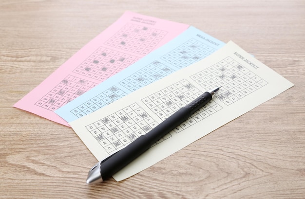 Lottery tickets and pen on wooden background