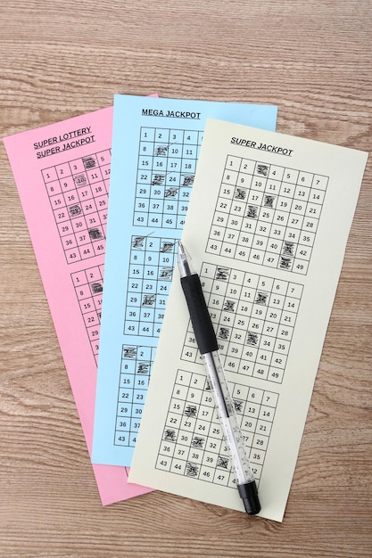 lottery tickets and pen on wooden background