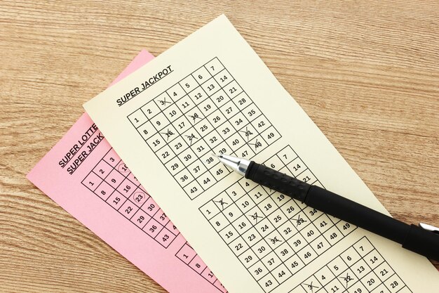 lottery tickets and pen on wooden background