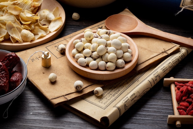 Lotus seeds Ancient Chinese medicine books and herbs on the table