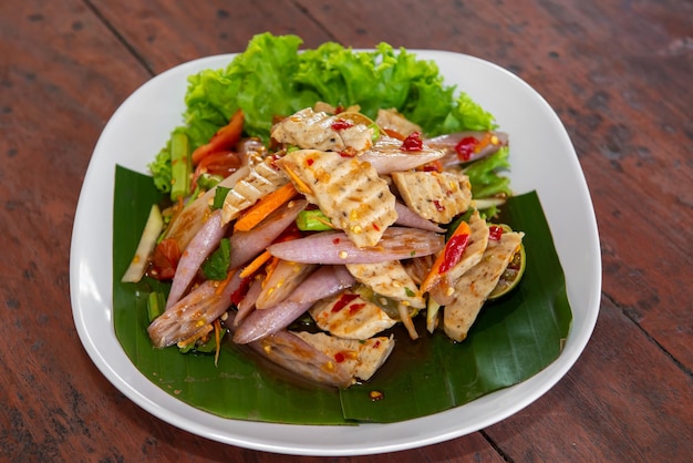 Lotus stem spicy salad with pork sausage on the wood table