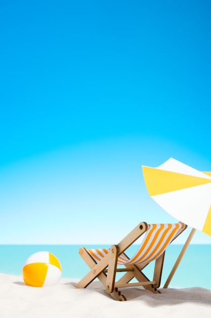 Lounge chair with parasol and beach ball on the coast, sky with copy space