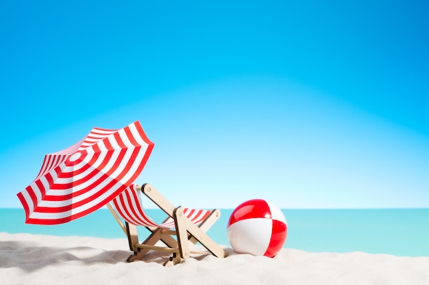 Кресло для отдыха с зонтиком и пляжным мячом на побережье, небо с копией пространства