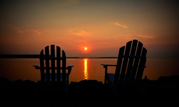 Photo lounge chairs on riverbank against orange sky