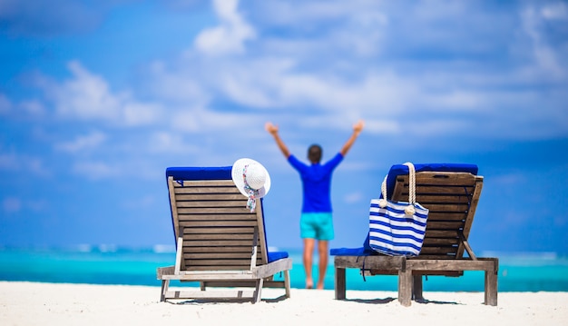 Photo lounge chairs with bag and hat on tropical white beach