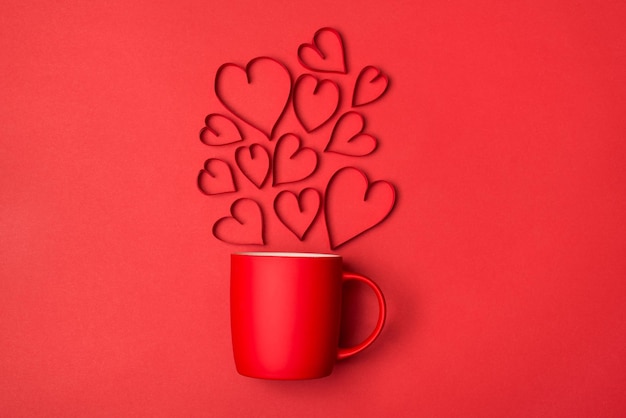 Любовь в воздухе завтрак на концепции дня святого валентина. Выше вид сверху фото ярко-красной чашки с летающими сердцами, изолированных на ярком цветном фоне