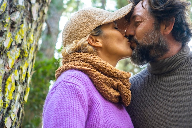 愛と関係大人のカップルの男性と女性が屋外でキスするロマンチックなシーンで一緒に森の屋外公園を背景にロマンスレジャー活動の人々