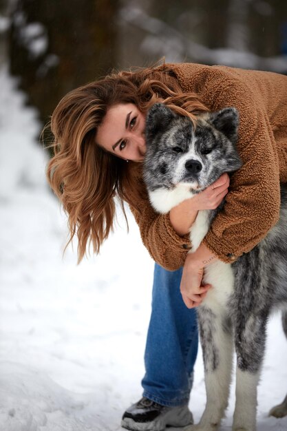 動物への愛ハスキー犬と雪の中で遊ぶ若い女性ペット愛好家犬人間の友達のコンセプト