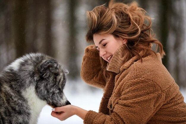 Love to the animals Young woman playing in the snow with a husky dog