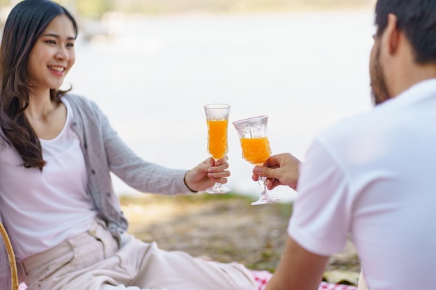 愛するアジア人カップルが公園でピクニックを楽しんでいます ピクニックの幸せなカップルがピクニックバスケットで一緒にリラックスしています