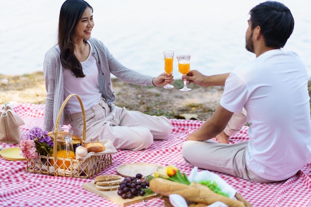 屋外の公園でピクニックタイムを楽しむ恋のアジアのカップル ピクニックバスケットで一緒にリラックスしたピクニック幸せなカップル