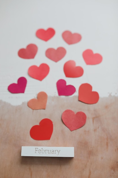 Love background with paper hearts and red ribbon on white background