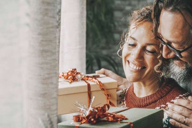 Foto amore e regali di natale concetto attività per il tempo libero con giovani maturi uomo e donna che si scambiano regali in vacanza invernale a casa con sorriso e felicità coppia in relazione abbraccia e divertiti insieme