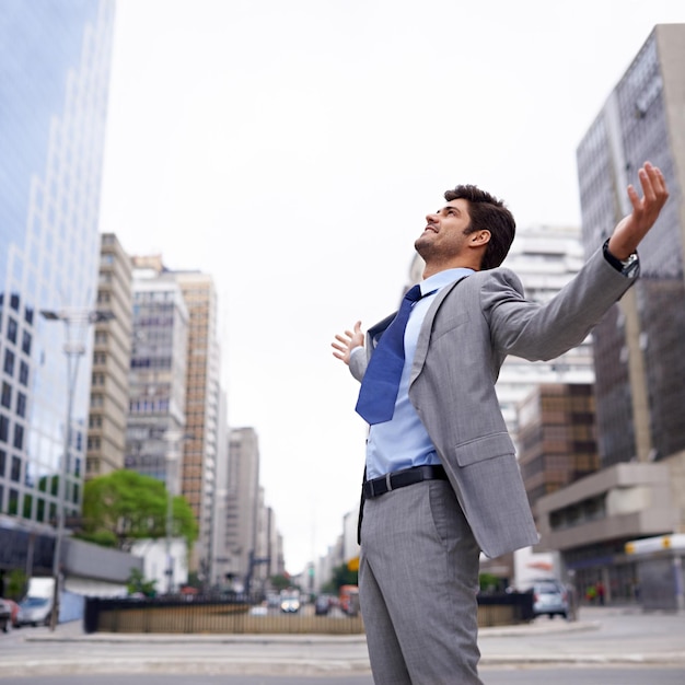 A love for the city A contented young businessman standing in the city with his eyes closed and his arms raised