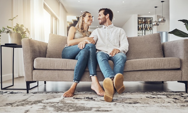 Photo love comfy and couple on the sofa to relax with a smile and gratitude in living room happiness laughing and happy man and woman comfortable on the couch for peace conversation and affection