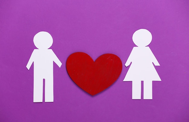 Love concept. Paper man and woman with a red heart on purple.