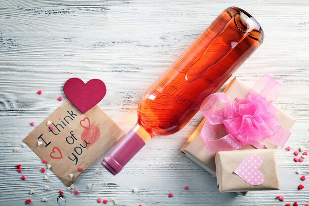 Love concept - wine bottle with decorations on white wooden background, close up