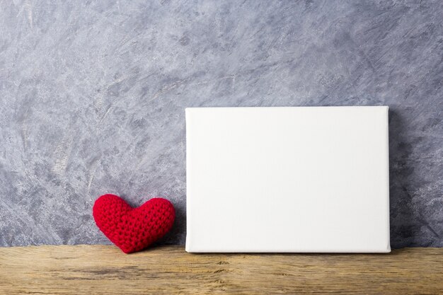 Love concepts of red heart and blank canvas frame on wood table for valentines day