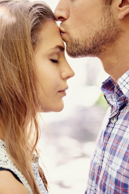 Foto coppia d'amore e bacio sulla fronte parco e felicità per incontri di relazione e tempo di qualità all'aperto romanticismo uomo e donna con affetto amorevole o legame con gesto romantico o bacio sulla testa