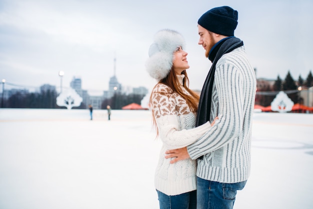 Amore coppia abbracci sulla pista di pattinaggio. pattinaggio invernale all'aria aperta, tempo libero attivo, pattinaggio sul ghiaccio, uomo e donna felici insieme