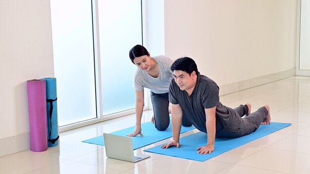 Love couple online learning yoga breathing and meditation together at home. Sport and Exercise for healthy. Asian woman and man lifestyle.
