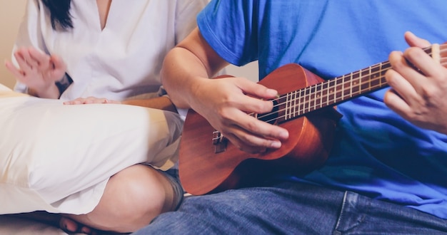 Любовь пара, играющая Укулеле и гитара в постели