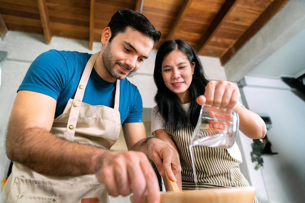 La coppia d'amore prepara la farina per l'impasto per la pizza fatta in casa e il dolce da forno per la torta dolce per il giorno di san valentino