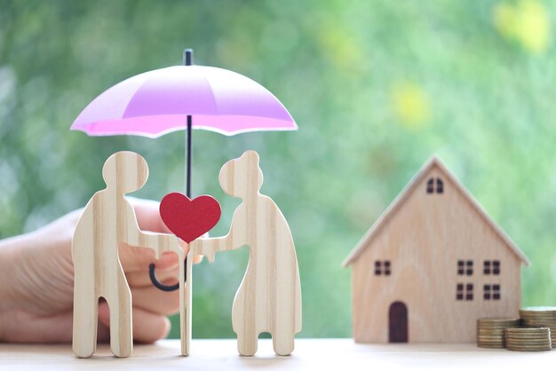 Love couple senior holding heart shape and model house on natural green background