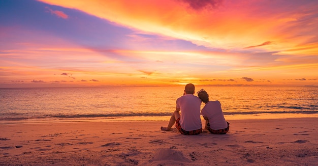 ビーチ旅行の夏休みに一緒に夕日を見ているカップルが大好きです。人々 のシルエットの海辺