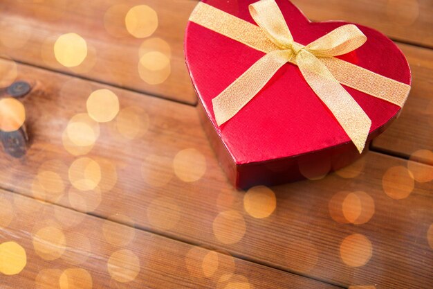 love, date, romance, valentines day and holidays concept - close up of heart shaped gift box on wood