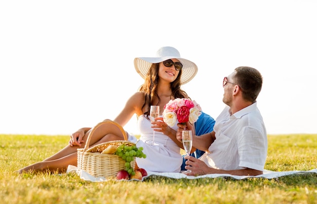 Concetto di amore, appuntamenti, persone e vacanze - coppia sorridente che beve champagne durante il picnic