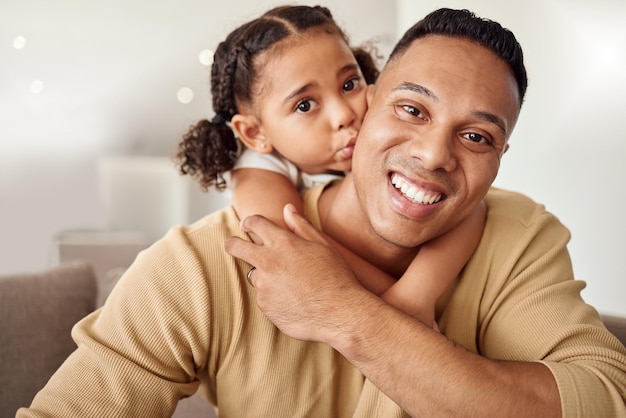 Love family and girl and father kiss on a sofa while bonding relax and hug in a living room in their home together Happy family smile and portrait of loving child embrace parent on couch indoors