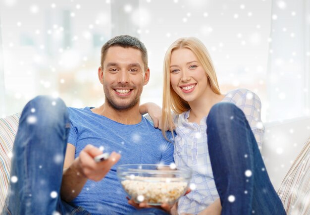 love, family, technology, entertainment and people concept - smiling couple watching tv and lying on sofa at home