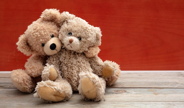 Love friendship concept tight hug Teddy bears couple on wooden floor red wall background