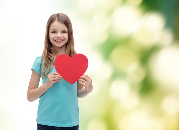 love, happiness and people concept - smiling little girl with red heart