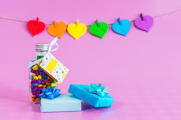 Photo love hearts with the colors of lgbt comfits and gifts on pink background