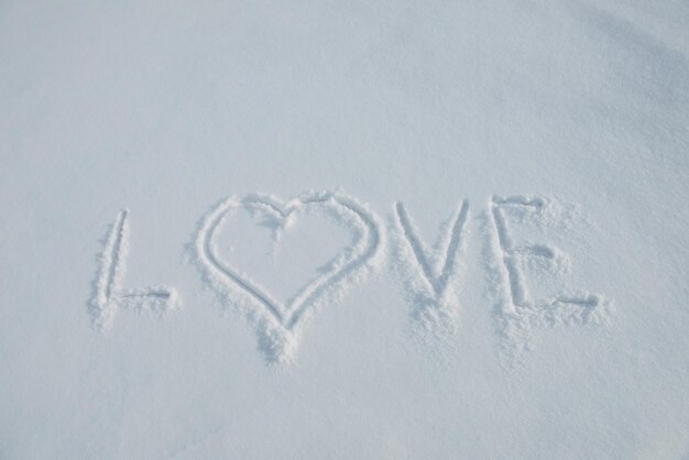 Love, inscription on white snow, close-up. Valentine's Day concept.
