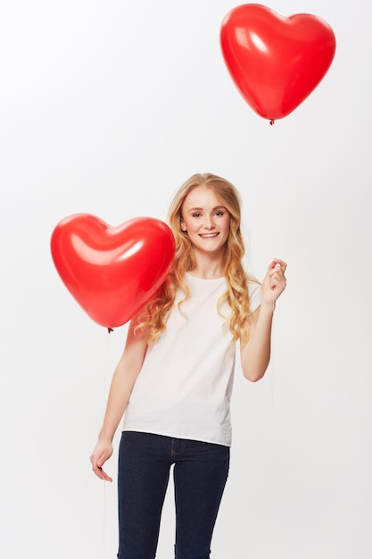 Love is in the air Cropped view of a young woman holding a red heart in a studio