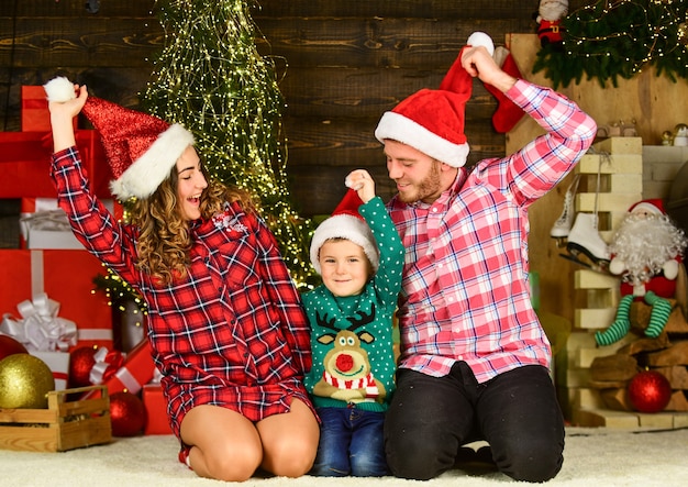 Love is in the air. happy family celebrate xmas. son with parents in santa hat. little kid boy love mom and dad. love spend holiday together. having fun. new year at home. family christmas portrait.