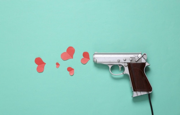 Love layout made with gun and hearts on mint green background\
creative valentines or romantic concept flat lay top view