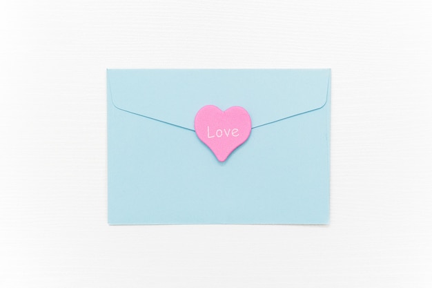 Love Letter. Blue closed envelope and pink heart with text LOVE on white