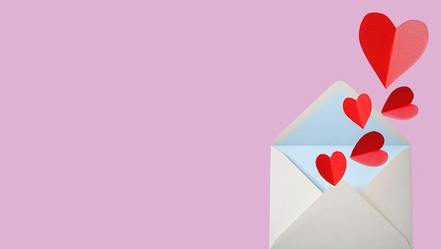 Love letter envelope with paper craft hearts flat lay on pink valentines or anniversary background